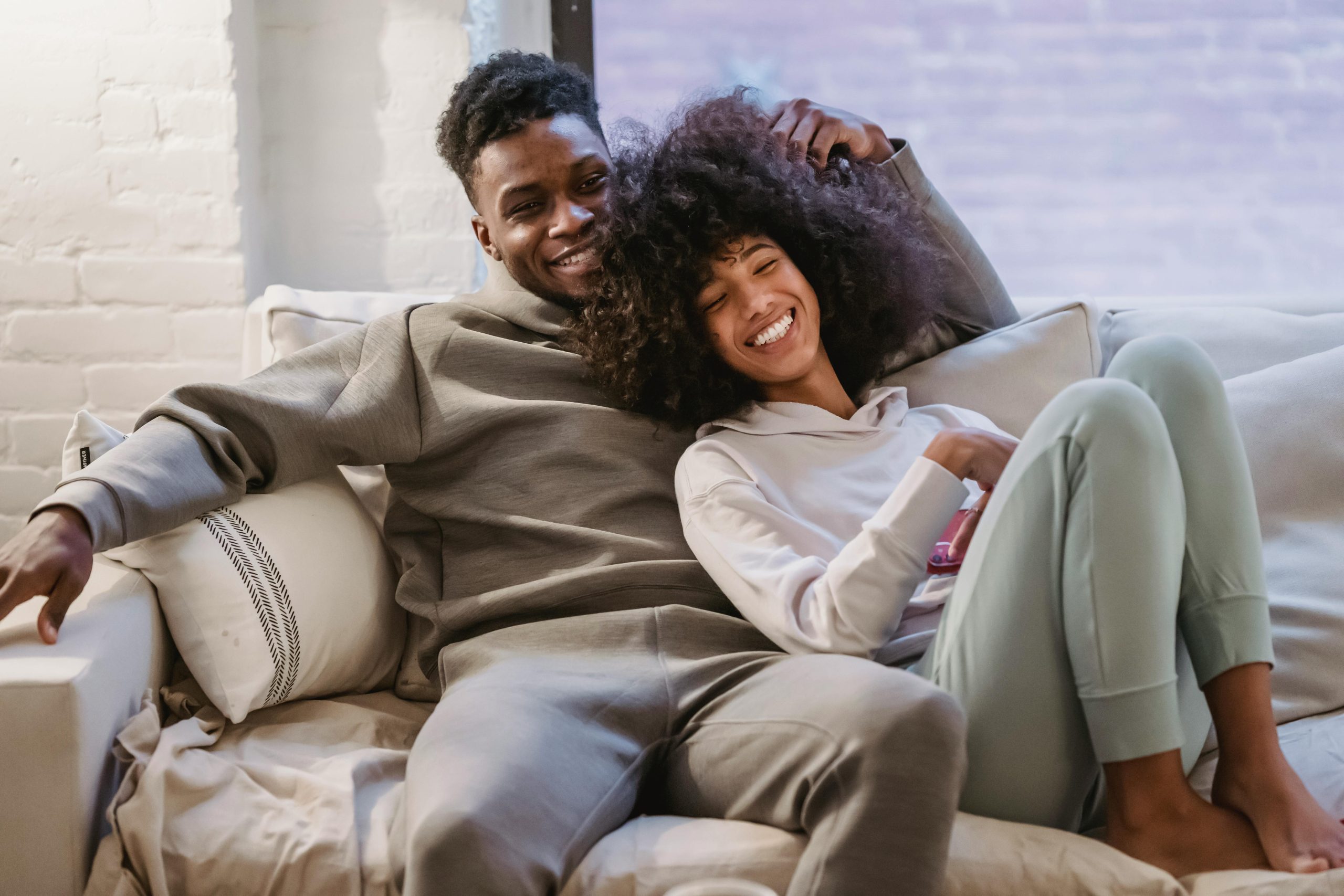 Young couple enjoying a cozy moment at home, smiling and relaxed on the sofa.